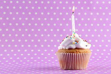 tasty birthday cupcake with candle, on purple background