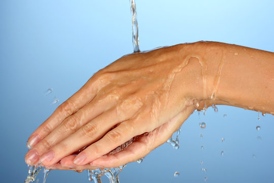 Washing hands on blue background close-up