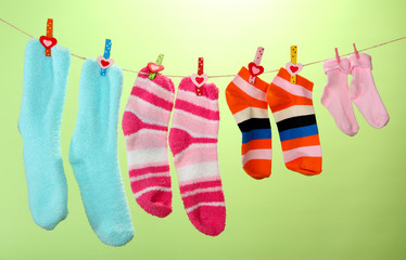 Colorful socks hanging on clothesline, on color background