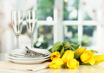 Yellow tulips and utensils for serving on room background