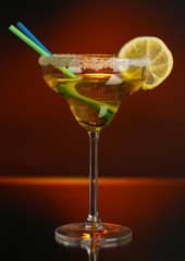 Yellow cocktail in glass on color background