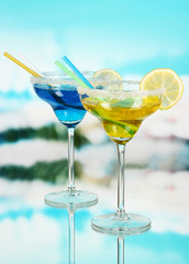Yellow and blue cocktails in glasses on blue natural background