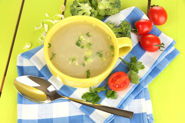 Diet soup with vegetables in cup on green wooden table close-up