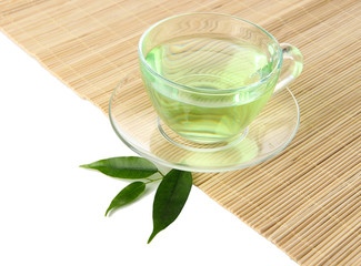 Obraz na płótnie Canvas Przezroczysty kubek zielonej herbaty na maty bambusowe, samodzielnie na białym tle