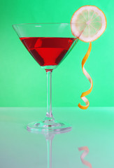 Red cocktail in martini glass on green background