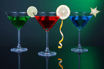 Alcoholic cocktails in martini glasses on dark green background