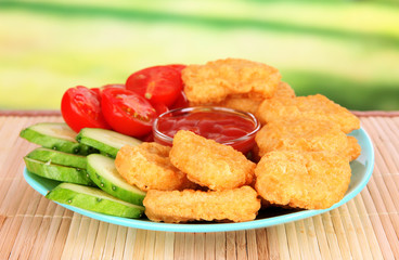 Fried chicken nuggets with vegetables and sauce on table in