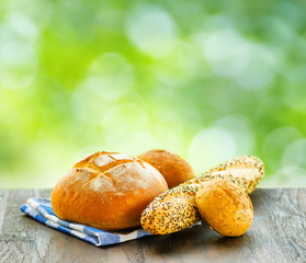 Fresh bread and checkered napkin on wooden table on rural backgr