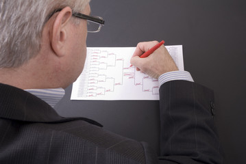 March Madness Businessman Crossing Out Teams on Bracket