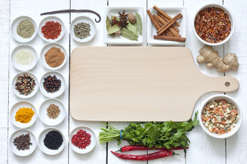 Fototapeta na wymiar Przyprawy i suszone warzywa z deska do krojenia na białym desek