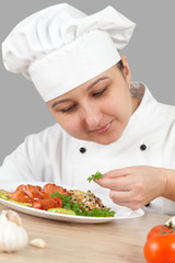 Woman chef puts vegetables on a plate
