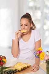 Beautiful young woman eating pineapple