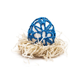Easter egg  in a nest. Blue ornament is knitted