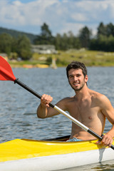 Smiling sporty man kayaking on lake