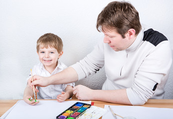 Father and little boy of two years having fun painting