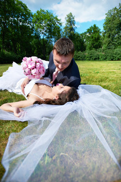 Happy bride and groom lying on grass
