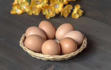 wicker basket full of raw eggs and yellow flower bouquets