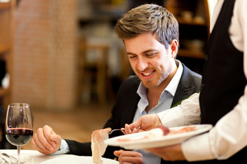 Waiter serving ham to a customer