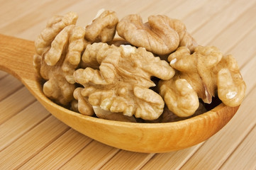 Shelled walnuts in wooden spoon close up