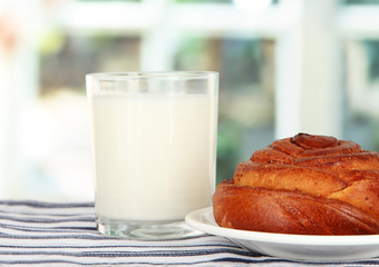 Bread roll and glass of milk on window background