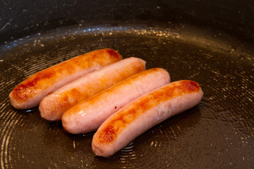 sausages frying in oil in the pan