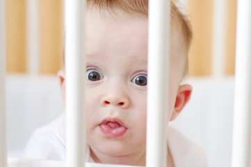Surprised baby in white bed age of 6 months