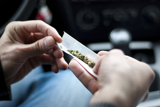 man making joint and a stash of marijuana in the car