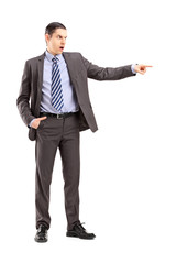 Full length portrait of an angry businessman pointing with his f