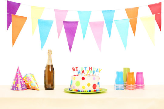 Bottle of sparkling wine, plastic glasses, party hats and birthd