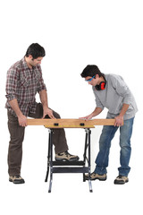 Father and son securing plank of wood