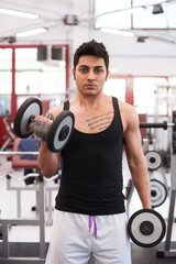 Young man exercising with dumbbells in a gym.