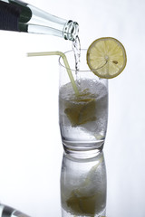 Mineralwasser mit Zitronen und Spiegelbild beim Einschenken