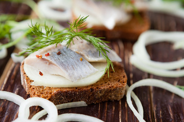 slices of salty herring on whole grain bread with dill