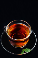 cup of black tea with mint on black background top view