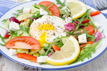 Vegetable salad with poached egg on a plate, closeup