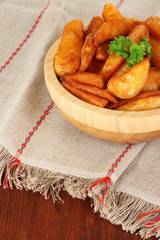 Appetizing village potatoes in bowl on wooden table close-up