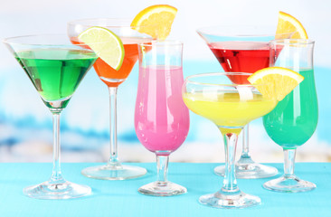 Glasses of cocktails on table near pool