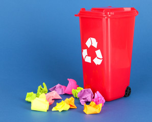Recycling bin with papers on blue background