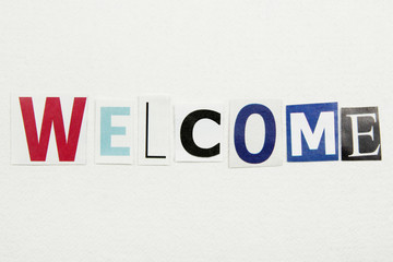word welcome cut from newspaper on white handmade paper