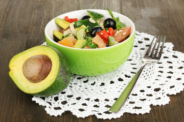 Tasty avocado salad in bowl  on wooden table close-up