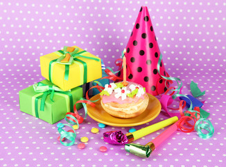 Colorful birthday cake with candle and gifts on pink background