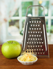 Metal grater and apple, on bright background