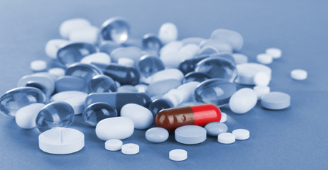 Assortment of pills, tablets and capsules in blue light