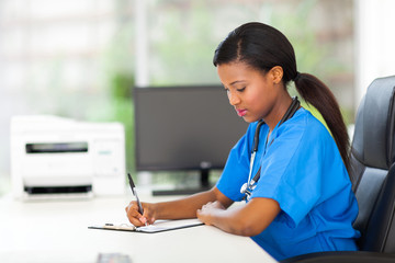 female african pediatric nurse writing medical reports