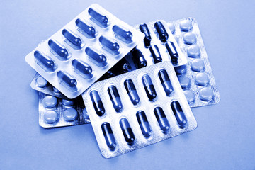 Capsules and pills packed in blisters in blue light