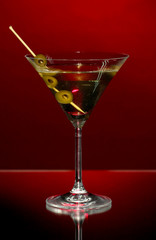 Martini glass and olives on dark background