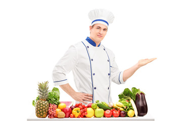 Male chef in a uniform gesturing with hand and posing behind a t