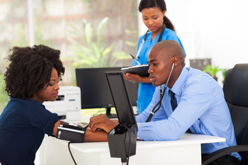african medical doctor monitoring patient's blood pressure