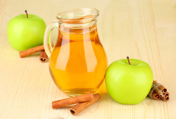 Full jug of apple juice and apple on wooden background