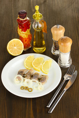 Dish of herring and spices on wooden table close-up